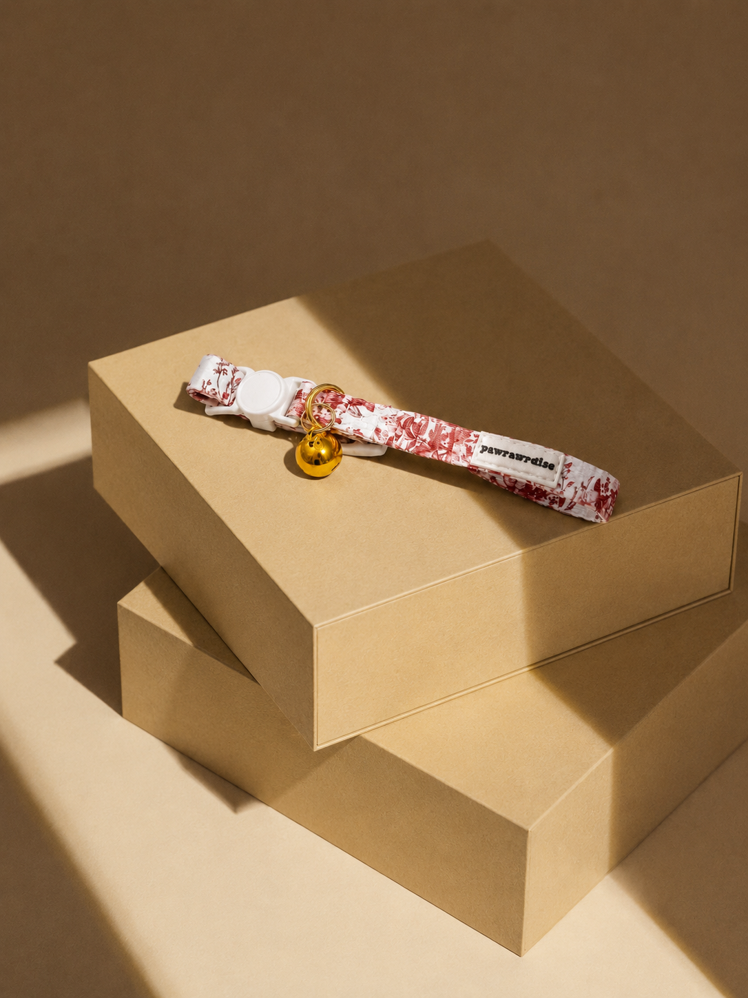 City of Love floral-patterned cat breakaway collar with a gold tag on a beige box against a brown background