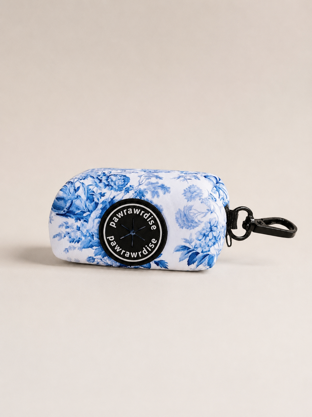 Enchanted floral-patterned dog poop bag holder with 'Pawrawrdise' branding on a beige background
