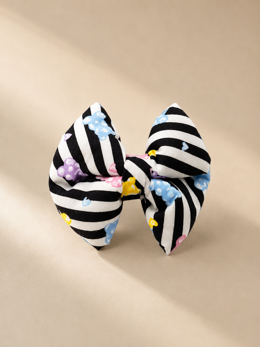 Black and white striped bow and jelly bears with colourful accents on a beige background
