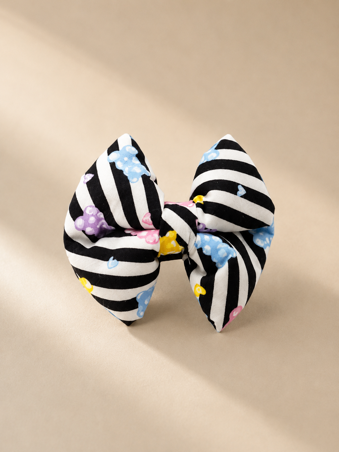 Black and white striped bow and jelly bears with colourful accents on a beige background