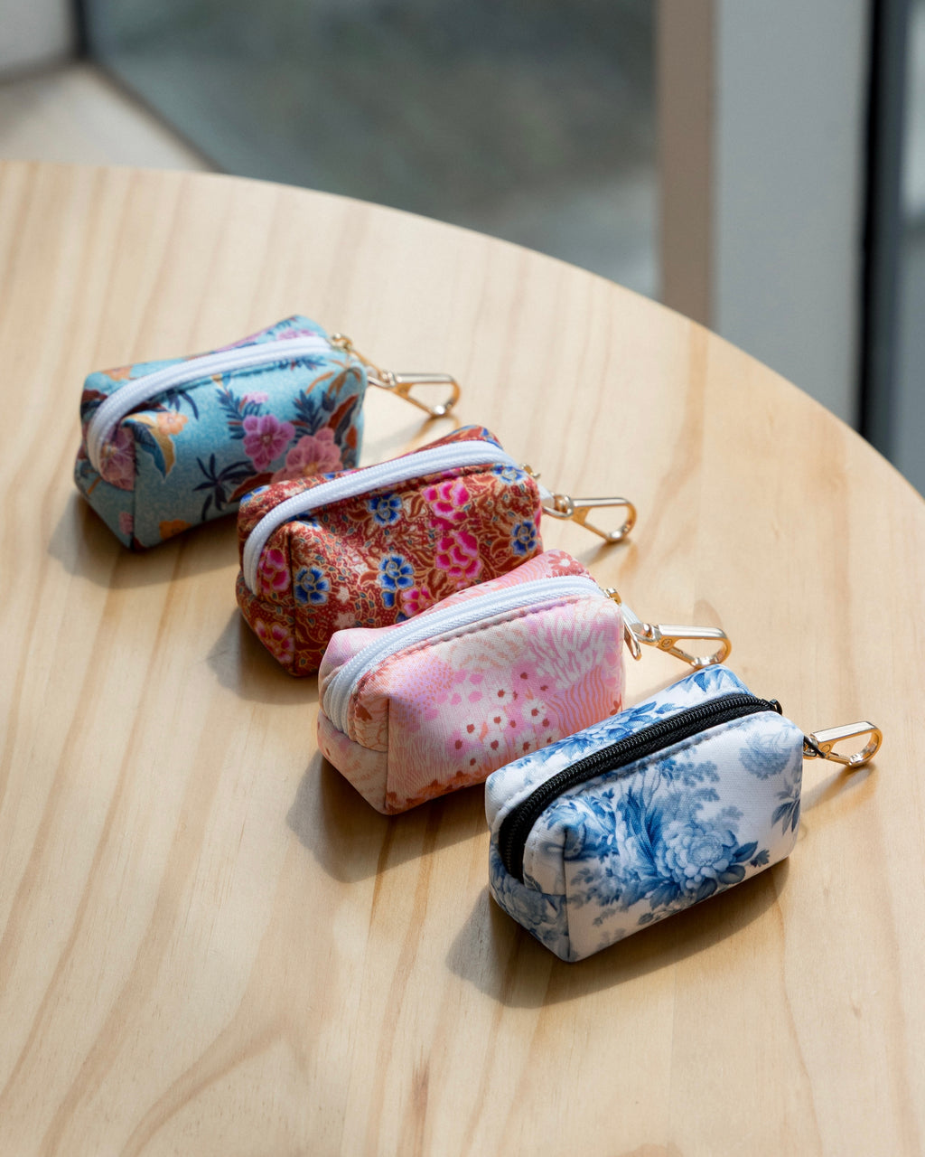 Set of four floral-patterned dog poop bag holder on a wooden surface