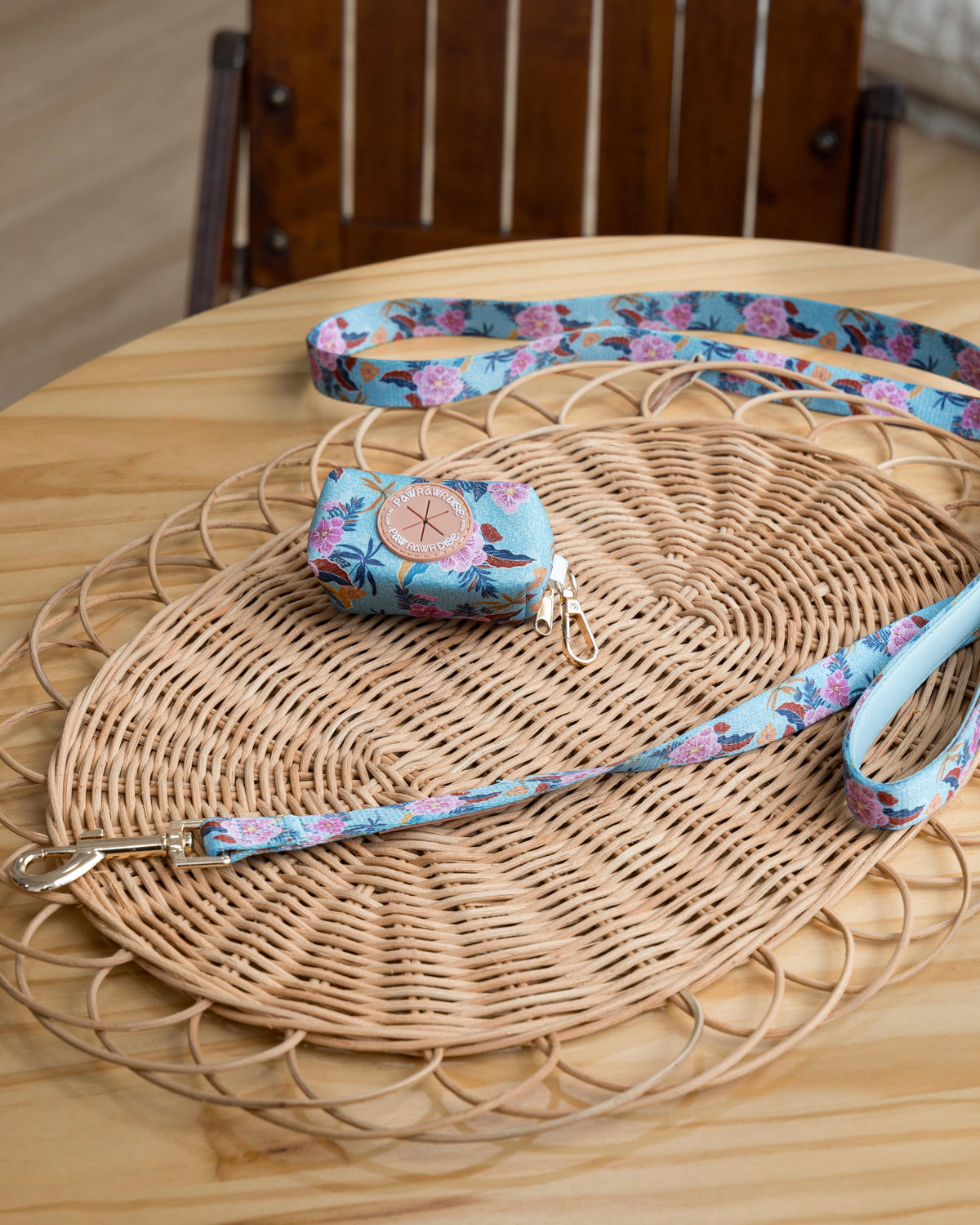 Floral-patterned dog leash and matching dog pouch on a woven mat