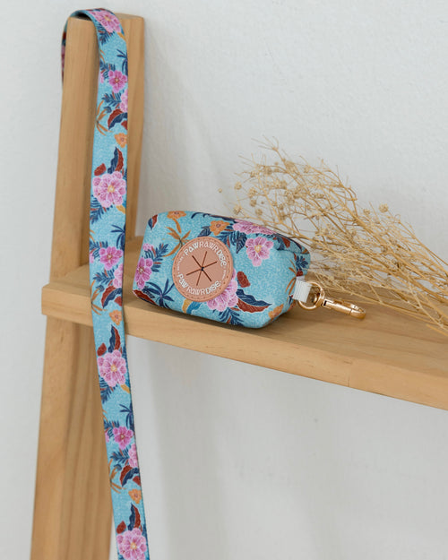 Floral-patterned pouch with strap on a wooden shelf against a white background
