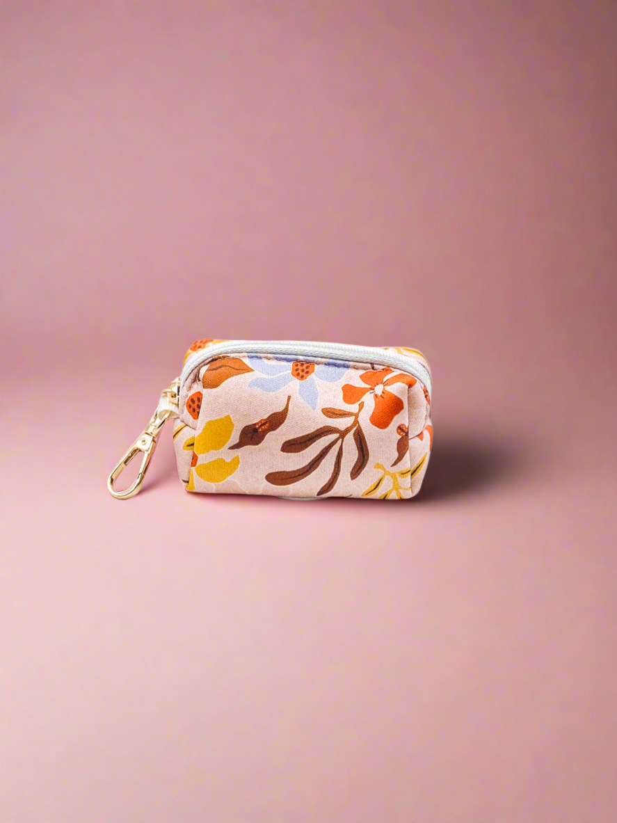 Summer floral-patterned pouch with a gold zipper on a pink background